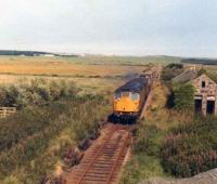 A class 26 powers up the gradient past the abandoned station at Rathen with the daily goods from Fraserburgh to Aberdeen, in August 1978.<br><br>[John Williamson 14/08/1978]