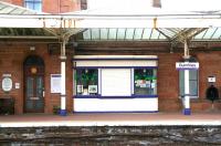 Traditionally a well kept station, a section of the down platform at Dumfries shows an interesting selection of <I>platform furniture</I> in May 2008. On the left above the wooden bench is a notice marking Dumfries as <I>Best Station 1987</I>. A tub of plants stands alongside the booking office door. An old platform kiosk, recently repainted, is being used to display art works. The former platform drinking fountain is on the right, with a red pillar box standing alongside. As for the canopy...<br><br>[John Furnevel 20/05/2008]