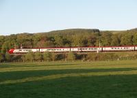 The setting sun lights up a northbound Voyager as it leans into a curve just south of the site of Scorton station. The M6 motorway is immediately behind the train, but thankfully screened by the trees so only the Bowland hills can be seen. <br><br>[Mark Bartlett 11/05/2009]