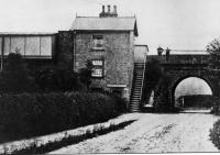 A very early picture of Scorton station, perched high on the WCML embankment. The wooden platform buildings can be seen alongside the stone built station house. The station closed on 1.5.39 and all trace has been swept away. [See image 23496] for a modern day comparison from the same viewpoint, looking west along Station Lane just outside the village. <br><br>[Rev Ron Greenall Collection //1900]