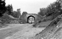 This is the rail bridge over the road at the north end of Boat of Garten during the demolition in June 1974. The embankment either side of the bridge has already been cut back prior to the removal of the arch. The road was being widened in conjunction with the new road bridge over the River Spey which was behind the camera. For several years there was a gap on the rail route from Boat of Garten to Broomhill. The original bridge was 3 tracks wide and was replaced by a single track rail bridge when the Strathspey Railway extended to Broomhill in the first years of the 21st Century.<br><br>[John McIntyre 16/06/1974]