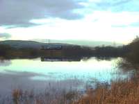 The causeway at Rishton sees a Northern Pacer crossing on its way to Colne with a late afternoon service. This structure divides a local reservoir in two. On the north side of the railway is a sailing club but on this side only the local wildlife.   <br><br>[Mark Bartlett 04/12/2009]