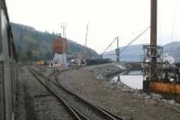 Eastern approach to Stromeferry in 1975, with a Howard Doris shunter [see image 28421] in the distance. The yard is a hive of activity with rail and sea freight, much of it destined for the HD oil platform construction yard at Loch Kishorn.<br><br>[Frank Spaven Collection (Courtesy David Spaven) //1975]