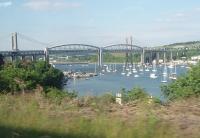 Brunel's famous Saltash suspension bridge over the Tamar estuary (or as it is technically known - lenticular truss viaduct), as seen from an approaching Penzance to Exeter train, which is just about to call at Saltash station and then swing sharply right onto the bridge approach. Under the left hand span the Ernsettle Royal Navy depot, rail served from the Gunnislake branch that runs along the far shore, can be seen.  <br><br>[Mark Bartlett 15/06/2010]