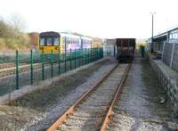 The 14.00 <I>Northern</I> DMU from Saltburn to Bishop Auckland slows for the Shildon stop on 23 November 2010. On this side of the fence is the NRM site with the north wall of the main exhibition hall to the right. The view is east from the end of the 'excursion platform' located within the site and shows one of the coal wagons for which Shildon works became famous during its later years (over 10,000 HAA wagons were built there - almost the whole fleet).<br><br>[John Furnevel 23/11/2010]