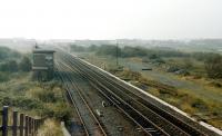 View north west at Stevenston no 1 signal box in 1985. The trackbed of the LMS connection to the Caledonian line to Montgomerie Pier is on the right with the abutment of the Caley bridge in the background.<br><br>[Colin Miller //1985]