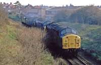 A train of Class 37s is seen shortly after passing through the former Felixstowe Beach station running towards the junction near Felixstowe. From there, the locomotives will head to Ipswich for servicing [see image 34707]. At the time, in April 1984, the heavy freightliner trains to the container port at Felixstowe were double-headed and this peculiar working helped ease the congestion on the line before the loop to Trimley was built.<br><br>[Mark Dufton 14/04/1984]