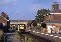 A July evening in 1991 at Oulton Broad South station with a DMU departing for Lowestoft. The original down platform fell into disuse in the mid 1980s following singling of the line and the adoption of RETB signalling between here and Westerfield to the south. In leaving this station, the specially equipped Class 101 DMU is thus re-entering the traditional signalling system.<br><br>[Mark Dufton /07/1991]