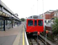 A District Line shuttle service stands in the bay at Kensington Olympia on 24 July 2005. It will shortly undertake the short return journey to High Street Kensington via Earls Court. The Olympia Exhibition Centre stands on the right.  <br><br>[John Furnevel 24/07/2005]