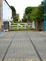 Extant track and crossing gates on Gordon Street, Pembroke Dock, looking east along trackbed that passes between the houses in the distance and crosses Water Street to access the station some 50 metres beyond [see image 39622].  <br><br>[David Pesterfield 23/05/2012]