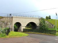 View east at Tomatin distillery in July 2012 showing the bridge carrying the Highland Main Line over the distillery access road and the adjacent burn. The signal for the north end of Tomatin loop can also be seen.<br><br>[Mark Bartlett 05/07/2012]