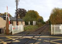The level crossing at Oyne looking towards the station site on 16 October 2012. Although the telegraph poles are still standing the wires appear to have been removed in this area. At the next former station to the east, Pitcaple, 4 wires were still in place towards Inverurie. [See image 35899]<br><br>[John McIntyre 16/10/2012]