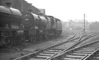 Monument Lane shed, Birmingham, looking west from the entrance to the shed yard, in November 1960. The line to Wolverhampton runs past off to the right, while to the left and behind the camera stands the large City Sawmill. Ex-LMS 40936, officially withdrawn from here in January 1961, is one of a pair of Compounds in the picture. The locomotive was cut up in September that year at nearby Cashmores, Great Bridge. The shed (closed 1962) and sawmill are long gone, with most of the area now occupied by the National Indoor Arena and car park.<br><br>[K A Gray 26/11/1960]
