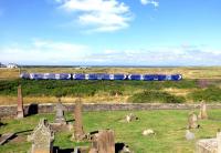 An Ayr to Glasgow Central class 380 service heads north, dead on schedule, shortly after calling at Prestwick Town on 30 July 2013. The graveyard of the 12th Century St Nicholas Church is in the foreground, with Old Prestwick Golf Course on the seaward side of the line. <br><br>[Colin Miller 30/07/2013]