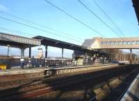 The new down side footbridge steps are sited approximately on the throat for the line into the former bay platforms at Wakefield Westgate. The view shows the north end of the original brick platform wall and the long concrete extension to beyond the new footbridge, together with a more recent short extension beyond. The roofline and clock tower seen through the canopy are located within the walls of the maximum security HM Prison Wakefield along the other side of Love Lane from the northern end of the station. <br><br>[David Pesterfield 04/02/2014]