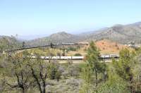 A very long container freight, with three locomotives at the head-end, on the Tehachapi Loop spiral in April 2014. Built by the Southern Pacific, the 19th century spiral is 0.73 miles of continious 2% grade.  Situated in the Tehachapi Pass in the California high desert, the arrangement enabled trains to ascend the pass between Mojave and Bakersfield.<br><br>[Brian Taylor 15/04/2014]