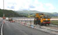A road-rail vehicle parked on the realigned track alongside the newly widened road leading to the rebuilt Pont Briwet on 6th July 2014. The line from Harlech to Pwllheli is due to reopen by September 2014.<br><br>[Colin McDonald 06/07/2014]