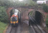 Pulling away from the Pokesdown stop in torrential rain on 23 May, 444023 on a Poole to Waterloo service passes through the twin arch bridge at the east end of the station. Thankfully, the station footbridge from which the photograph was taken has a full length roof.<br><br>[Mark Bartlett 23/05/2014]
