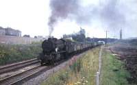 A WD Austerity 2-8-0 clatters through Cumbernauld with a rake of mineral wagons in August 1965.<br><br>[G W Robin 03/08/1965]