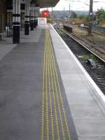 In a change from the small ribbed paving flag normally added to the rear of the platform coping flags, lines of yellow plastic studs, glued to the tarmac, have been used at Wakefield Westgate. Early morning view along the platform on 29 August 2014.<br><br>[David Pesterfield 29/08/2014]
