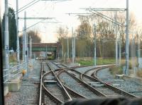 Driver's view of the now connected and operational junction for the new Manchester Airport tram line at St Werburgh's Rd. The tram is about to diverge from the old railway formation onto brand new tracks and a Metrolink service from East Didsbury is being held while the Airport service crosses the Up line. [See image 44201] for the same location in 2013.<br><br>[Mark Bartlett 02/12/2014]