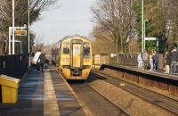 A Manchester Victoria to Leeds semi fast service passes Mills Hill in east Manchester on 29 November 2014 as passengers wait on both platforms for the next stopping services.<br><br>[John McIntyre 29/11/2014]