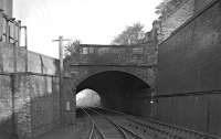 Old undated photograph looking north west through Ladhope Tunnel (which in reality is a wide bridge to accommodate a very skew crossing under the A7 road). Note the connection to a siding which once existed on Ladhope Vale in Galashiels. Early 20th century OS maps show It serving a loading dock, although its precise purpose is not obvious. Also of interest is the shanty building above the tunnel mouth - no doubt it housed workshops of some sort. The bridge itself was to see many changes in the years ahead [see image 22401].<br><br>[Bill Jamieson Collection //]