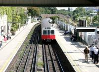 A Wimbledon - Barking District line train approaching West Brompton station on a warm and sunny afternoon in July 2005. West London Line platforms 3 & 4 stand to the right beyond the metal fence.  <br><br>[John Furnevel 22/07/2005]