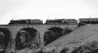 The empty stock of the Royal Train crossing the viaduct over the Duddo Burn at West Learmouth near Coldstream on 5 July 1962 behind Dalry Road Black 5s 45476 and 45477. The train was on its way from St Boswells to Coldstream to collect HM the Queen following a Royal visit before returning to London via Tweedmouth and the ECML. [Ref query 6558]<br><br>[Bruce McCartney Collection 05/07/1962]