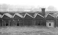 Mirfield shed was a typical LMS rebuild of an ex-L&YR standard shed, with a single roof pitch over each shed road and the original north light pattern roof retained over workshops and stores to one side. Closed in April 1967, the buildings were still substantially intact over six years later. Photographed from Woodend Road on the south side of the Calder Valley main-line.<br><br>[Bill Jamieson 28/10/1973]