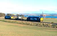 DRS 37218 and 37605 top and tail the nuclear flask train southwards between Invergordon and Alness on 1 May 2015. In the background the Cromarty Firth, with a couple of drilling platforms awaiting a recall to the North Sea.<br><br>[John Gray 01/05/2015]