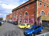 The Dryden Street facade of Edinburgh Corporation Tramway's former Shrubhill depot and works in May 2015. Having survived demolition for so long it is a pity this building is a target for graffiti (sorry, street art). Added to the scene are some cars which will cause nostalgic head-shakings in future decades.<br>
<br><br>[David Panton 11/05/2015]
