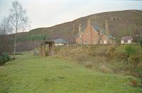 The Mound seen from the trackbed of the Dornoch Light Railway in 1998. The station platform can be seen in the distant left. The 'mainline' is beyond the station building seen to the right. Base of water tank to the right of the branch trackbed.<br><br>[Ewan Crawford //1998]
