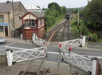A once common sight that is very rare now. The signalman at Ramsbottom has released the pedestrian wicket gates and winds the wheel to open the level crossing to road traffic as a passenger train disappears towards Rawtenstall. During the early 1960s this box was open 24/7, apart from a few hours overnight Sunday to Monday, and the line was busy with freight, parcels and passenger trains.<br><br>[Mark Bartlett 26/07/2014]