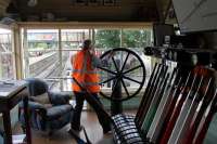 Signalman Peter Bendall winds the wheel in Ramsbottom signal box to close the level crossing gates to road traffic on 3rd August 2016. Peter believes these are the only wheel operated gates on a UK heritage railway so they are a cherished asset, if a little heavy to work. The large windows give excellent views of the railway and also the road on both sides of the crossing. Image taken with kind permission of the East Lancashire Railway during a supervised visit.  <br><br>[Mark Bartlett 03/08/2016]