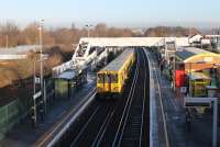 Merseyrail 507006 pulls away from Aintree heading for Ormskirk on 7th February 2017. The bright sunshine has made a large gold horseshoe in the middle of the footbridge almost invisible in this image. The old excursion platforms used by race goers are still partly in place behind the left hand platform.<br><br>[Mark Bartlett 07/02/2017]