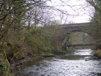 The railway viaduct just south east of Calderpark Halt once loomed high over both the North Calder Water and the still extant road bridge in the photograph. The long demolished viaduct crossed the river at an angle and continued above the left abutment of the road bridge seen here. Apart from a very short section on the west bank of the river where one of the viaduct abutments survives, the solum on both sides of the river crossing has since been landscaped and built over.<br><br>[Colin McDonald 15/02/2017]