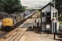 Class 37 hauled passenger train passing south through Kingussie station by the signalbox.<br><br>[Ewan Crawford //]