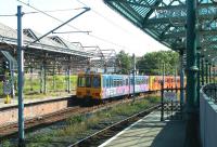 The south end of Tynemouth station in July 2004 with a Metro service arriving from Newcastle. The abandoned and overgrown excursion platforms stand in the background.<br><br>[John Furnevel /07/2004]