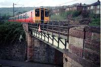 Westbound train leaves Old Kilpatrick over  roadbridge to its west.<br><br>[Ewan Crawford //]