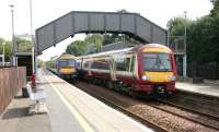 An eastbound stopping train leaving Lenzie in July 2006, just as an express passes through the westbound platform en route to Glasgow Queen Street. <br><br>[John Furnevel 26/07/2006]