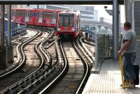 Scene at Poplar DLR station in July 2005. A Stratford - bound service is approaching the platform while a Lewisham branch train waits on the flyover in the background for the clear into West India Quay station. The transformation of the old London Docklands has been quite staggering - and still it goes on. (Anyone remember the Harry Enfield character <I>Loadsamoney</I>?)<br><br>[John Furnevel 21/07/2005]