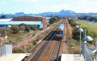 With Arthurs Seat and Edinburgh Castle forming a backdrop, a Glasgow shuttle speeds west about to pass through Edinburgh Park. 0906.<br><br>[John Furnevel /09/2006]