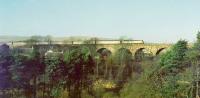 A Glasgow - Edinburgh Push-Pull service clatters across Castlcary viaduct in August 1988 with the houses of the village standing amongst the trees below. View from the South East.<br><br>[Brian Forbes /08/1988]