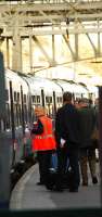 A ScotRail employee assists an older couple onto the train by carrying their luggage.<br><br>[Ewan Crawford 11/11/2006]