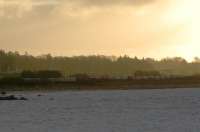 Freight for Fort William comes out of the sunrise at Craigendoran Junction but has to wait for the Helensburgh to Glasgow service to clear the junction.<br><br>[Ewan Crawford 04/01/2007]