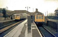 Rural junction in the rain. Maiden Newton, Dorset, in April 1975. A DMU departs on the Weymouth - Yeovil line as a train for the West Bay branch (at that time cut back to Bridport) prepares to leave. [See image 29077]<br><br>[Ian Dinmore /04/1975]