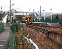 An eastbound service arrives at Camelon station in January 2007. After crossing the bridge over the A9 road, part of which can be seen in the foreground, the train will pass the remains of the former station.<br><br>[John Furnevel /01/2007]