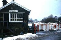 Crossing - keeper and local swap news at Wensley LC in 1982. View looks west along Wensleydale towards Redmire and Hawes. The old station (now a holiday cottage) is directly behind the box.  <br><br>[John McIntyre //1982]