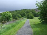 Looking east towards Upper Port Glasgow, the trackbed here ran straight and level to a bridge crossing the road to a small cutting which was in amongst the trees in the centre of shot behind the houses<br><br>[Graham Morgan 23/05/2007]